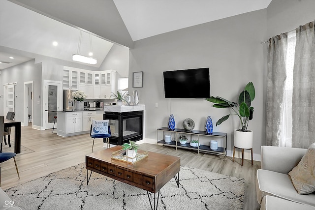 living room with high vaulted ceiling and light wood-type flooring