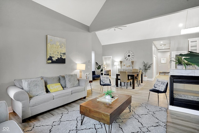 living room featuring a multi sided fireplace, ceiling fan, hardwood / wood-style floors, and high vaulted ceiling