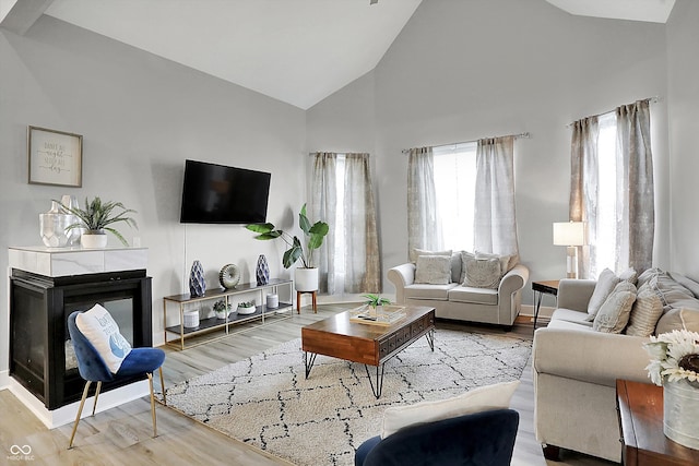 living room featuring a multi sided fireplace, high vaulted ceiling, and wood-type flooring