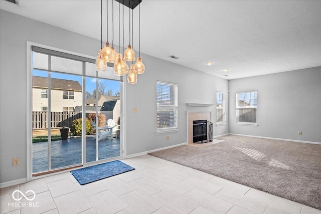 unfurnished living room with an inviting chandelier, light colored carpet, and a fireplace