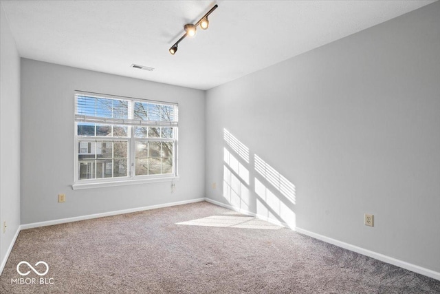 unfurnished room featuring light colored carpet and rail lighting