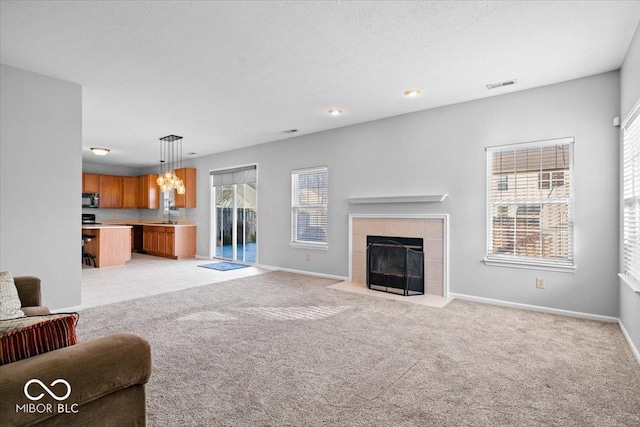 unfurnished living room featuring light colored carpet, a fireplace, sink, and a textured ceiling