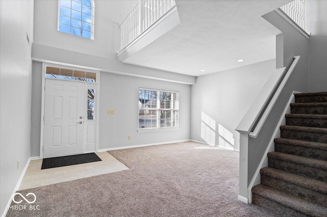 carpeted foyer with a high ceiling and a textured ceiling