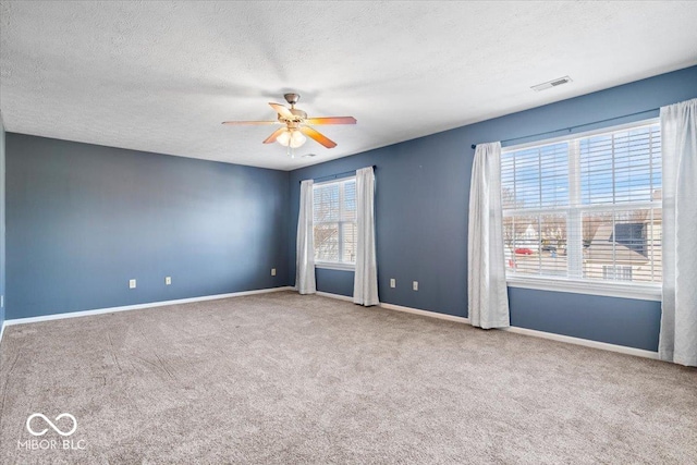 empty room featuring a textured ceiling, ceiling fan, and carpet