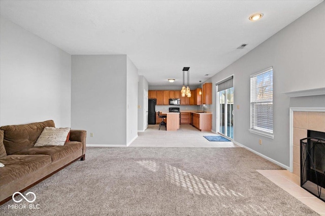 living room featuring a tile fireplace, sink, and light colored carpet