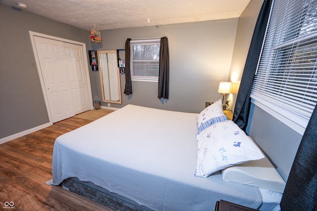 bedroom featuring a textured ceiling, dark hardwood / wood-style floors, and a closet