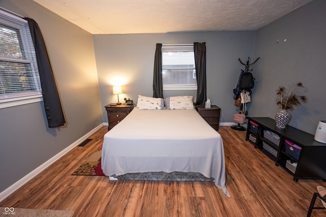 bedroom with dark hardwood / wood-style floors and a textured ceiling