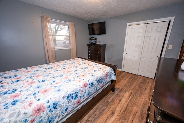 bedroom featuring dark wood-type flooring, a closet, and a textured ceiling