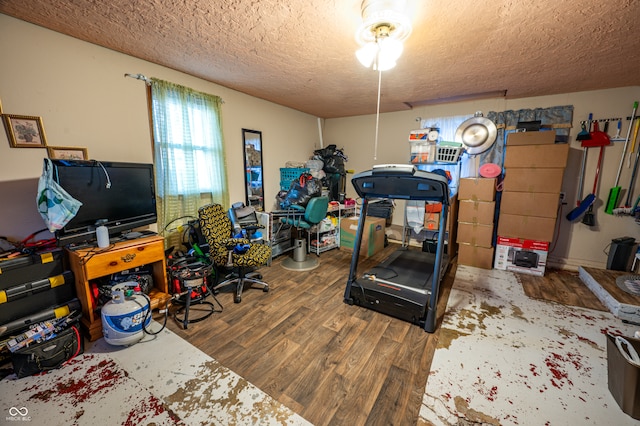 exercise room with wood-type flooring and a textured ceiling