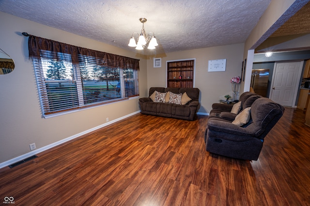 living room featuring dark hardwood / wood-style flooring, an inviting chandelier, and a textured ceiling