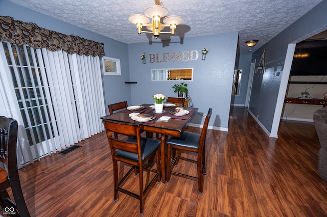 dining area featuring a textured ceiling, dark hardwood / wood-style floors, and a chandelier