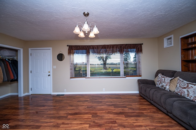 living room featuring a chandelier, a textured ceiling, and dark hardwood / wood-style floors