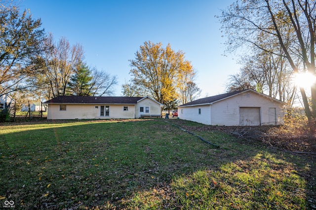 back of property with a garage, an outdoor structure, and a yard