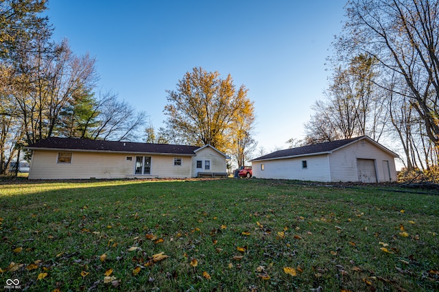 back of house with a garage, a yard, and an outdoor structure