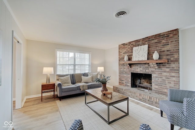 living room with ornamental molding, a brick fireplace, and light hardwood / wood-style flooring