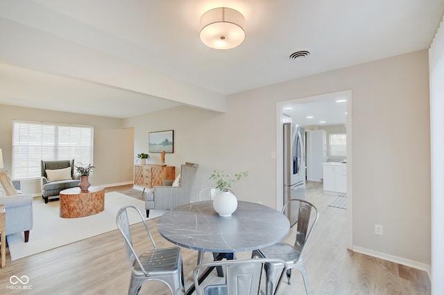 dining space with beamed ceiling and light hardwood / wood-style floors