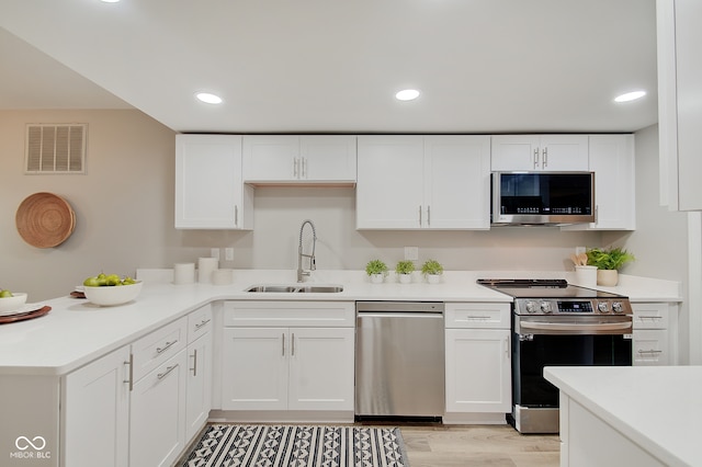 kitchen featuring stainless steel appliances, white cabinetry, sink, and light hardwood / wood-style flooring