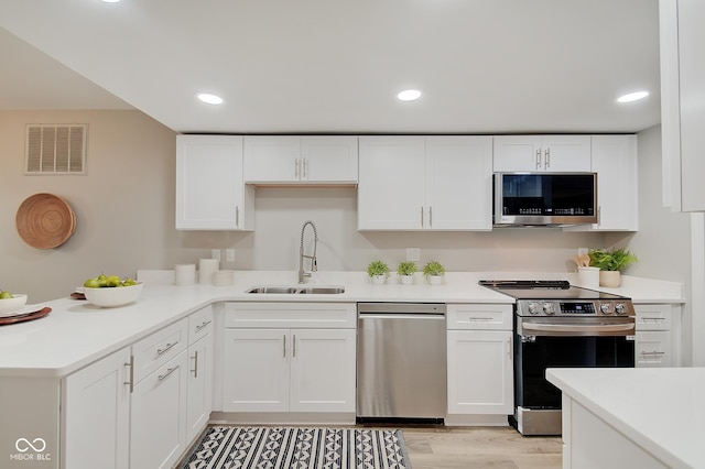 4902 N Capitol Ave, Indianapolis, IN 46208 - kitchen featuring stainless steel appliances, a sink, white cabinetry, light countertops, and recessed lighting