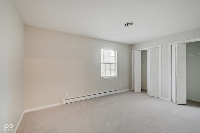 unfurnished bedroom featuring baseboard heating, multiple closets, and light colored carpet