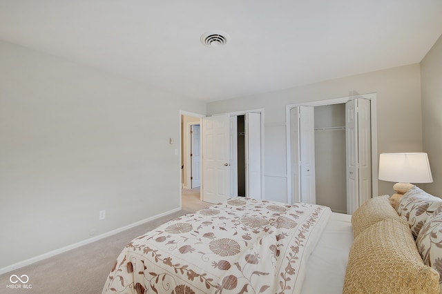 bedroom with light colored carpet and two closets