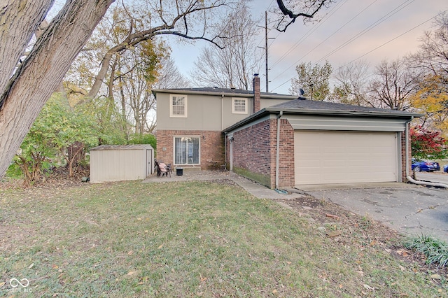 4902 N Capitol Ave, Indianapolis, IN 46208 - back of property featuring brick siding, asphalt driveway, an attached garage, a lawn, and a chimney
