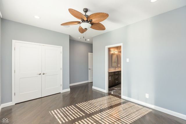 unfurnished bedroom featuring ensuite bath, ceiling fan, a closet, and dark wood-type flooring