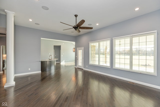 unfurnished living room featuring dark hardwood / wood-style floors, ceiling fan, and decorative columns