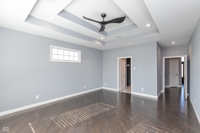 unfurnished room featuring a raised ceiling, ceiling fan, and dark hardwood / wood-style flooring