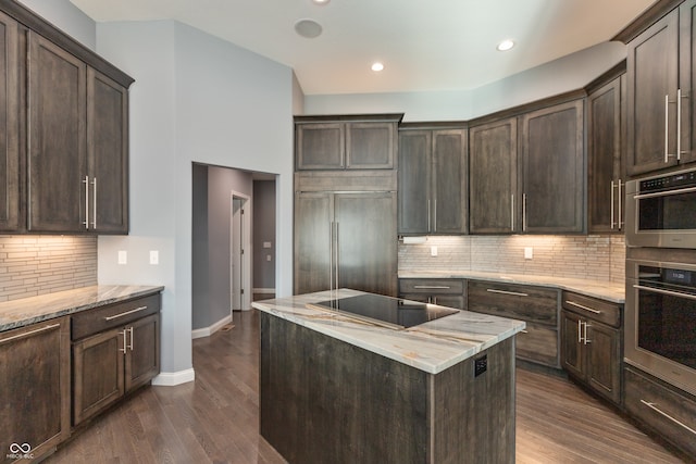 kitchen featuring dark brown cabinets, black electric stovetop, dark hardwood / wood-style floors, and paneled refrigerator