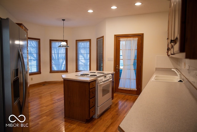 kitchen with white range, stainless steel fridge with ice dispenser, sink, pendant lighting, and hardwood / wood-style floors