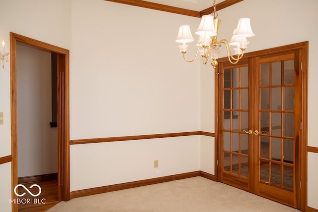 empty room with french doors, carpet floors, ornamental molding, and a notable chandelier