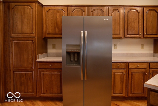 kitchen with light hardwood / wood-style floors and stainless steel fridge with ice dispenser