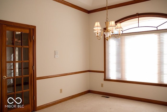 carpeted empty room featuring crown molding and an inviting chandelier