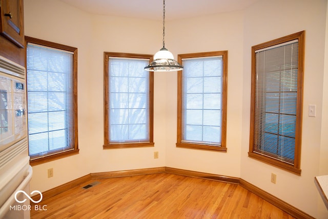 unfurnished dining area with wood-type flooring and an inviting chandelier