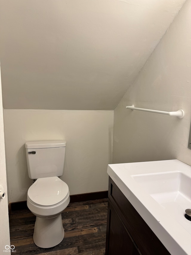 bathroom featuring hardwood / wood-style floors, vanity, lofted ceiling, and toilet