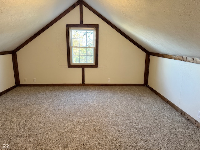 bonus room with vaulted ceiling, carpet floors, and a textured ceiling