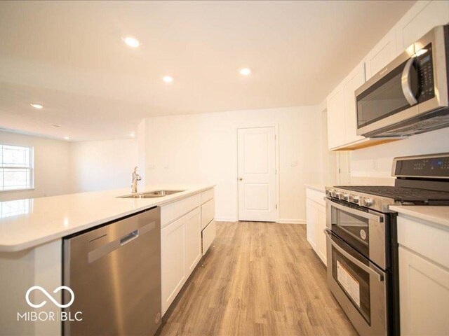 kitchen with sink, white cabinetry, stainless steel appliances, and light hardwood / wood-style flooring