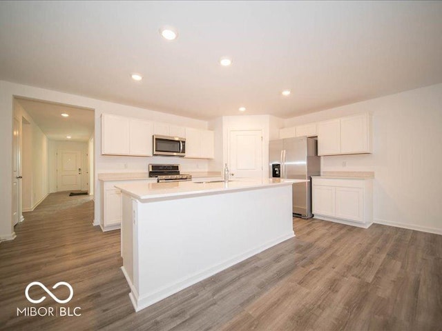 kitchen with white cabinetry, an island with sink, wood-type flooring, and appliances with stainless steel finishes