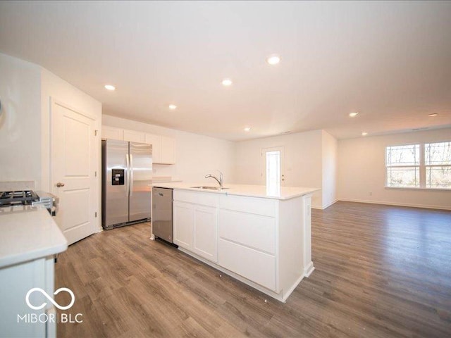 kitchen with stainless steel appliances, sink, hardwood / wood-style flooring, a center island with sink, and white cabinets