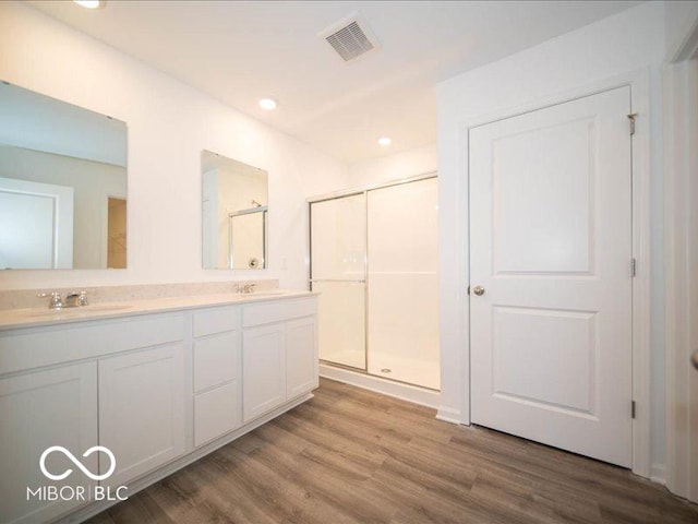 bathroom featuring hardwood / wood-style floors, vanity, and a shower with shower door