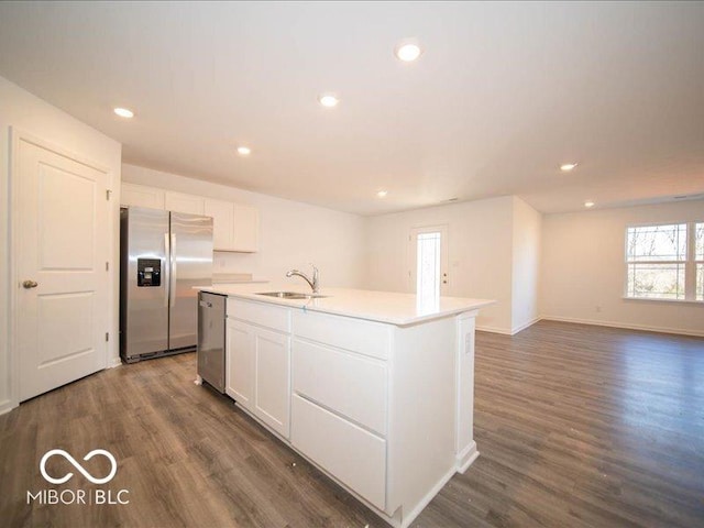 kitchen with white cabinetry, sink, dark hardwood / wood-style floors, a center island with sink, and appliances with stainless steel finishes