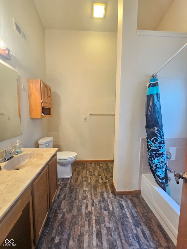 full bathroom featuring hardwood / wood-style floors, vanity, shower / bath combo, and toilet