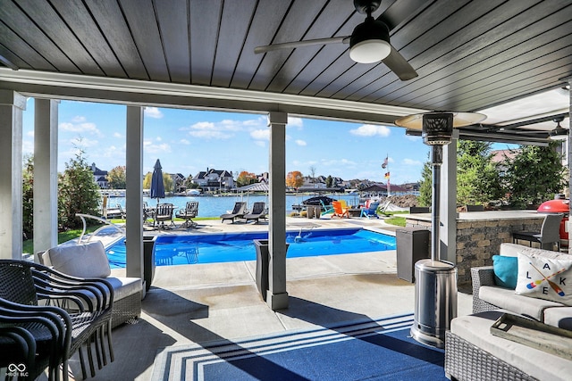 view of pool with ceiling fan, a water view, and a patio