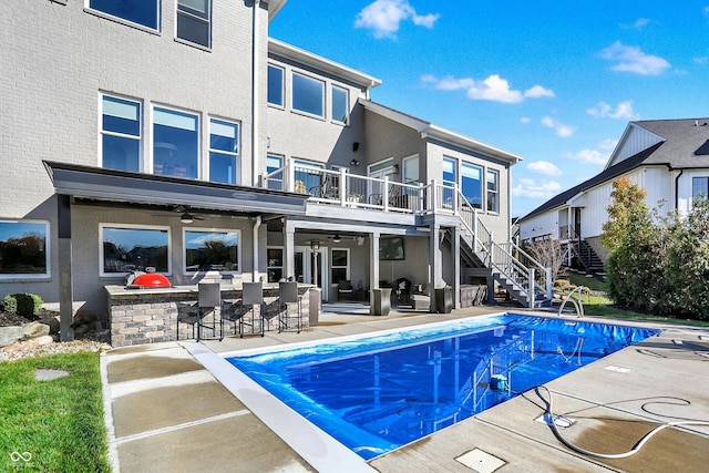 back of house featuring a bar, a patio, a covered pool, and ceiling fan