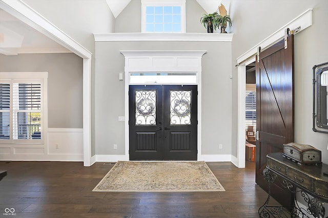 entrance foyer with french doors, a barn door, dark hardwood / wood-style floors, and high vaulted ceiling