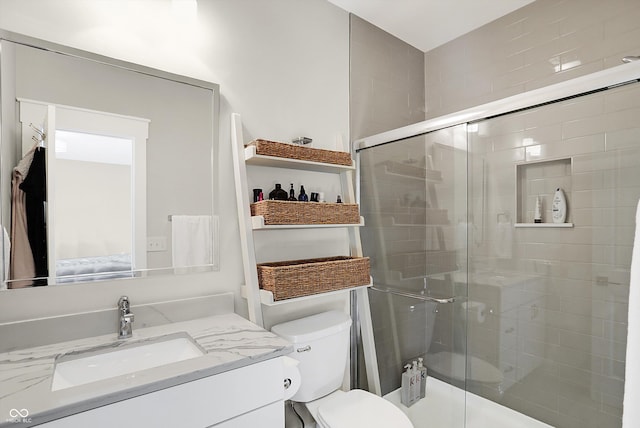 bathroom featuring vanity, toilet, and a shower with door