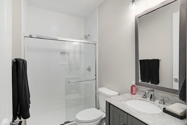 bathroom featuring vanity, toilet, and a shower with door