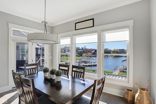 dining area with dark hardwood / wood-style flooring, a water view, and a wealth of natural light