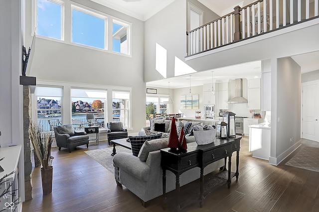 living room featuring a towering ceiling, dark hardwood / wood-style floors, plenty of natural light, and a water view