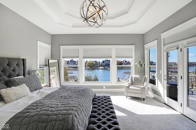 bedroom featuring carpet flooring, access to outside, a tray ceiling, a water view, and a chandelier